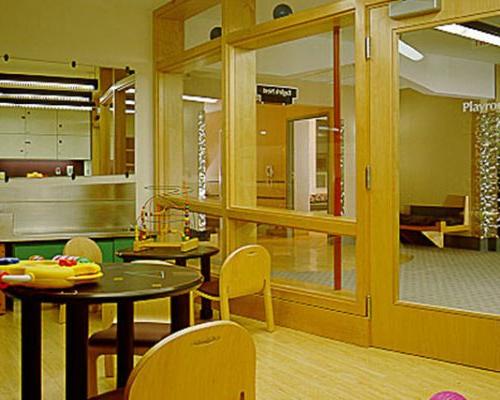 Interior photo of children's play area. Glass windows and door separate room from hallway